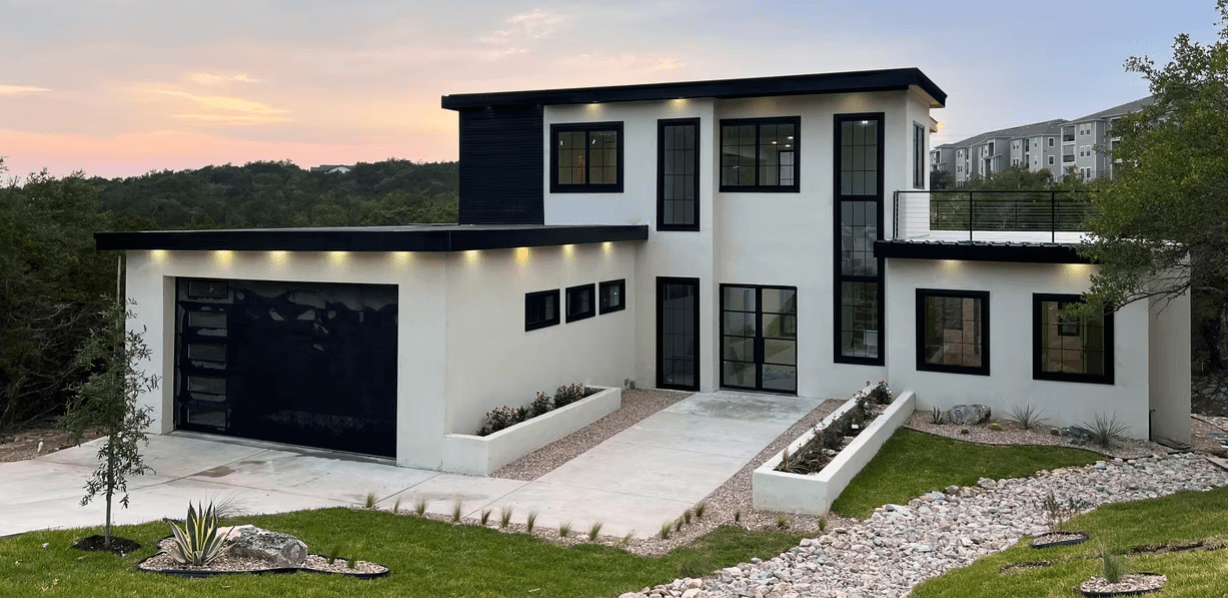 Completed AAC concrete home with modern exterior, black-framed windows, and desert landscaping at sunset