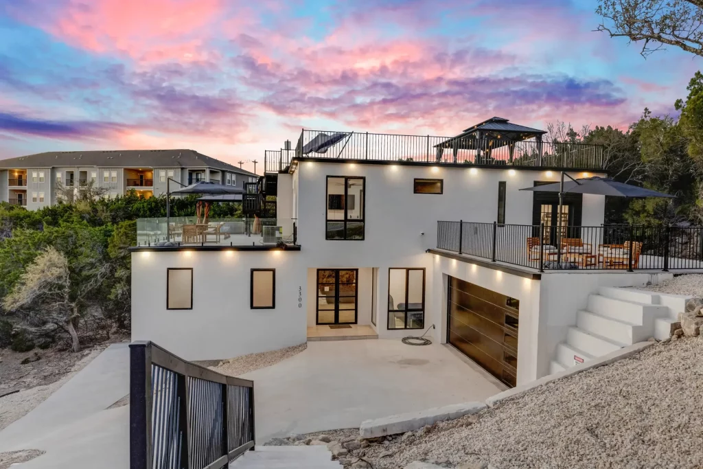 Multi-level AAC concrete home with white exterior walls and balconies set in hill country terrain