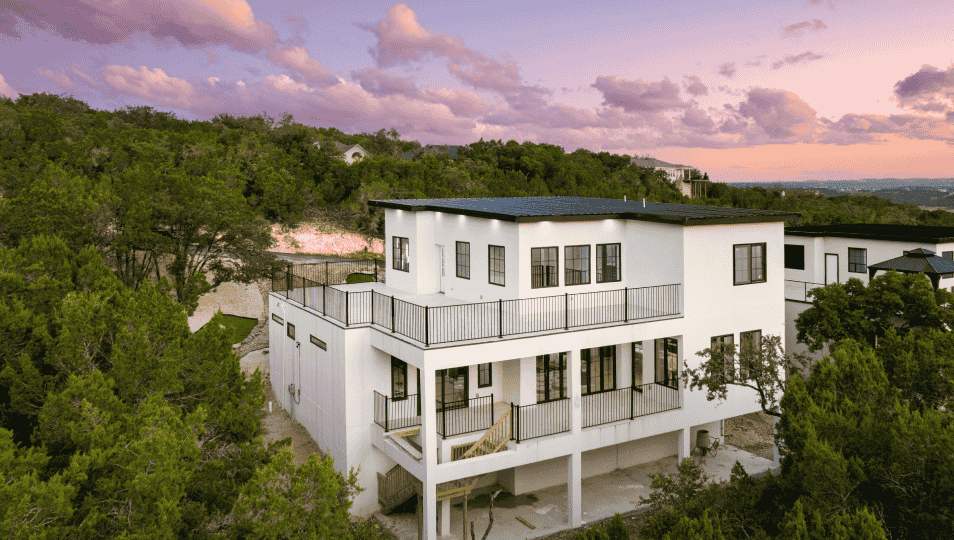Multi-level AAC concrete home built by MOTIVA Properties surrounded by hill country landscaping at sunset