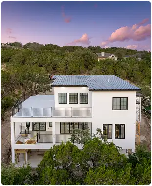 Three-story AAC concrete home with balconies and metal roof nestled in Texas Hill Country